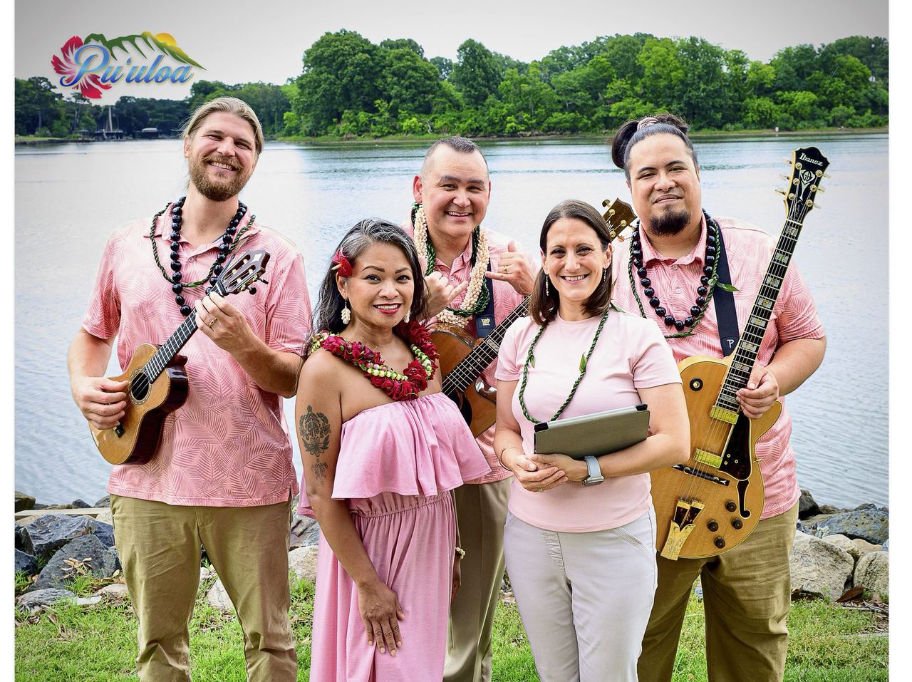 Puʻuloa Hawaiian Band, the live-music ensemble of Lilikoi Productions, standing together by the water